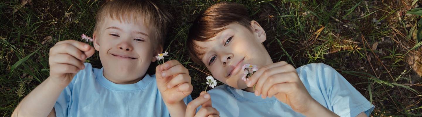 Two boys smiling with flowers in their hands