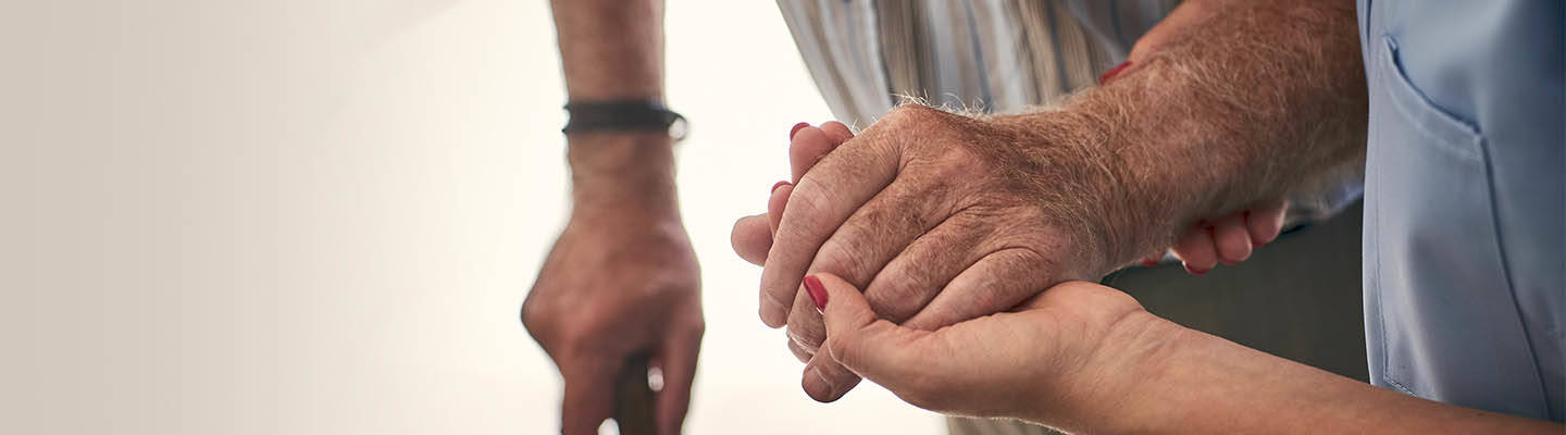 nurse holding hand of elderly man