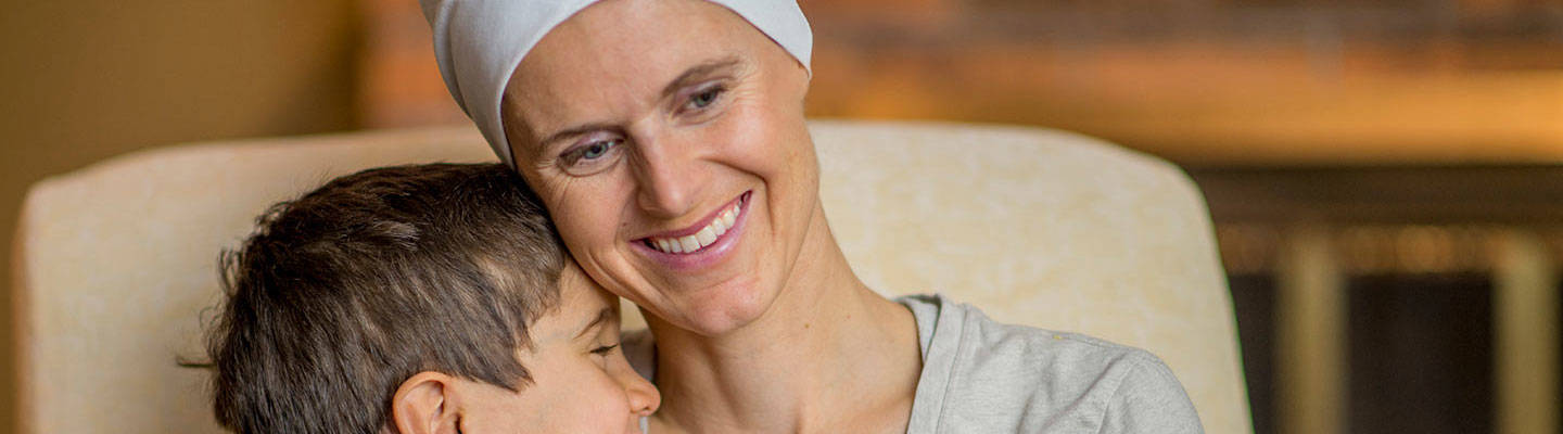 Woman with cancer wearing headband holding a child