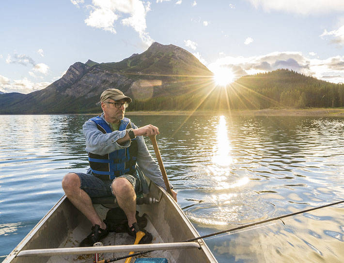 man paddling canoe on mountain lake
